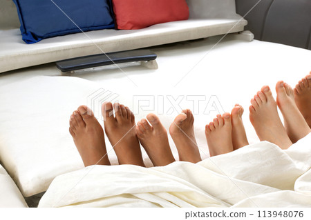 many children's feet peeking from under the blanket 113948076