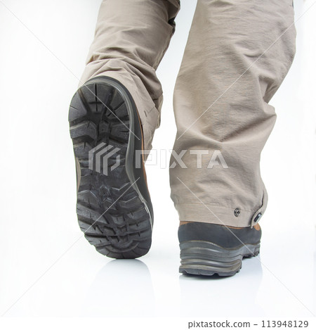 Trekking boots for hiking on the legs of a tourist on a white background 113948129