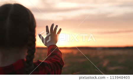 Girl dreamily reaches for sun with hand. Symbolism striving for light wisdom spiritual enlightenment knowledge self-development aspirations. Expectation of miracle dreams inspiration of young child. 113948403