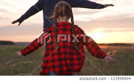 Happy family runs across field, daughter father imagine as airplane pilots dreaming inspired striving aspirations for more. Girl child kid man guy dad run to sun with arms outstretched at sunset dawn. Happy family runs across field, daughter father imagine as airplane pilots dreaming inspired striving aspirations for more. Girl child kid man guy dad run to sun with arms outstretched at sunset dawn. 113948404