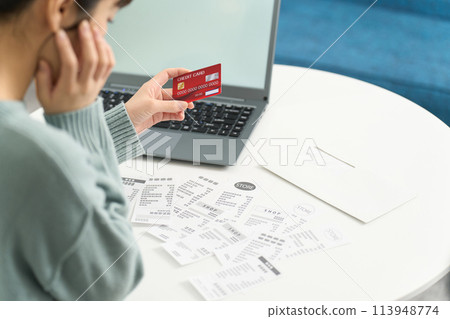 A woman worried about overspending on her credit card A woman worried about overspending on her credit card 113948774