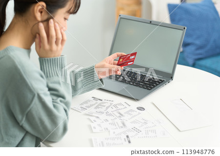 A woman worried about overspending on her credit card A woman worried about overspending on her credit card 113948776