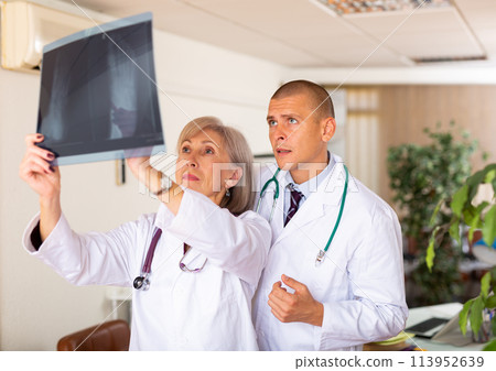 Two doctors examining x-ray of patient and discussing diagnosis 113952639