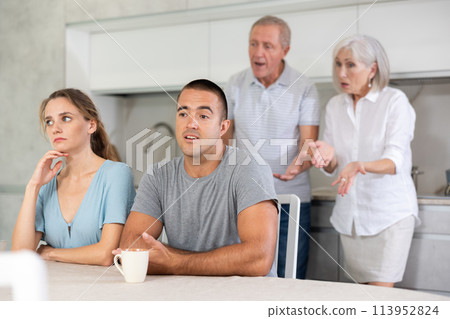 Elderly parents make claims to young couple in kitchen 113952824