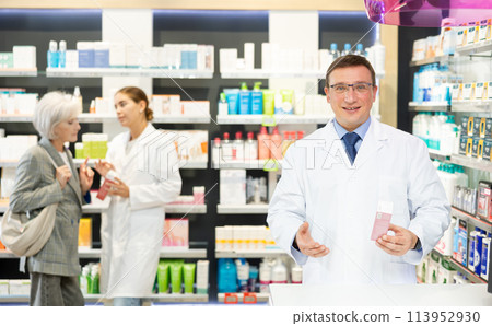 Middle-aged male pharmacist demonstrating preparation in box 113952930