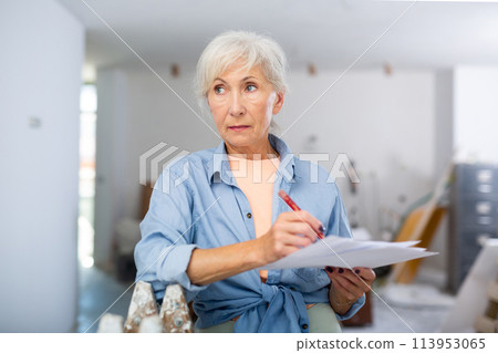 Portrait of woman filling documentation during repair works in construction site 113953065