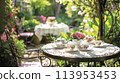 A charming English tea garden with wrought-iron tables and floral teacups 113953453