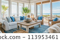 coastal-inspired living room with nautical decor, blue and white color palette, and natural textures such as rattan and driftwood. featuring panoramic views of the ocean through floor-to-ceiling 113953461