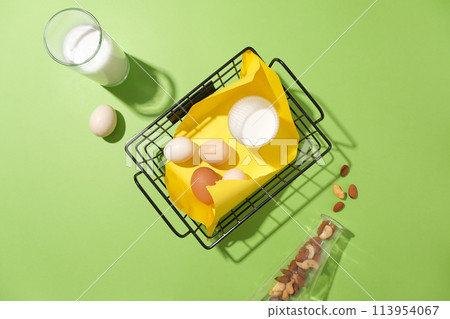 Top view of cooking concept on pastel green background. Flat lay with eggs and a cup of milk on basket. Layout for baking recipe, culinary, cooking blog 113954067