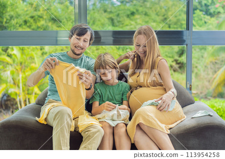 Heartwarming family moment as expectant mom, dad, and son joyfully browse through newborn baby's clothes, eagerly anticipating the arrival of a new family member Heartwarming family moment as expectant mom, dad, and son joyfully browse through newborn baby's clothes, eagerly anticipating the arrival of a new family member 113954258