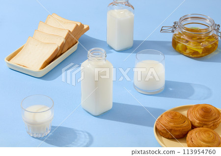 On the blue surface, some bottles and cups of milk are displayed with a jar containing ginger jam. A dish of sandwiches and a dish of bread are featured. Breakfast content On the blue surface, some bottles and cups of milk are displayed with a jar containing ginger jam. A dish of sandwiches and a dish of bread are featured. Breakfast content 113954760