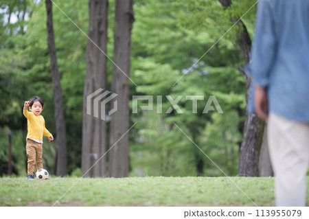 Father playing with boy kicking a soccer ball 113955079