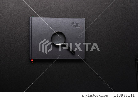 Black notebook and magnifying glass. Magnifying glass on a notebook. Search for information. Black Internet. 113955111