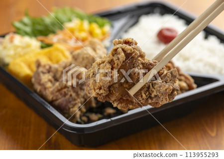Pick up and eat the fried chicken in your bento with chopsticks 113955293