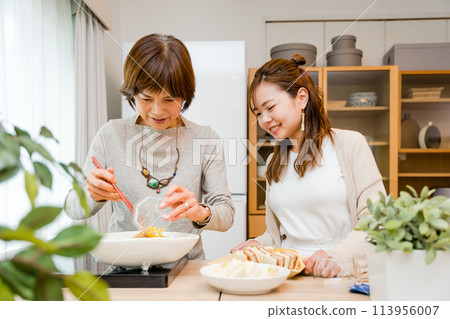 Mother and daughter serving food in the kitchen 113956007