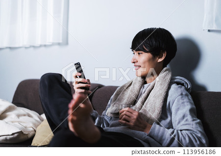 A Japanese man in his 30s operating a smartphone in his room after a shower with a glass in his hand A Japanese man in his 30s operating a smartphone in his room after a shower with a glass in his hand 113956186