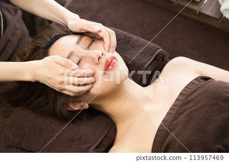 Young woman is receiving a facial massage. 113957469
