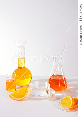 Transparent podium in round shaped for displaying product arranged with a boiling flask, erlenmeyer flask, beaker of orange liquid. Concept scene stage showcase for product made from natural orange ex 113957969