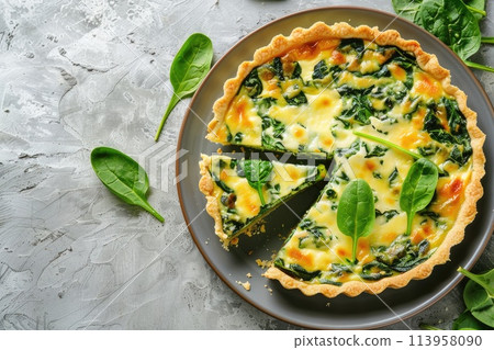 Savory tart of rich egg custard, spinach and cheese with cut out a slice on the plate 113958090