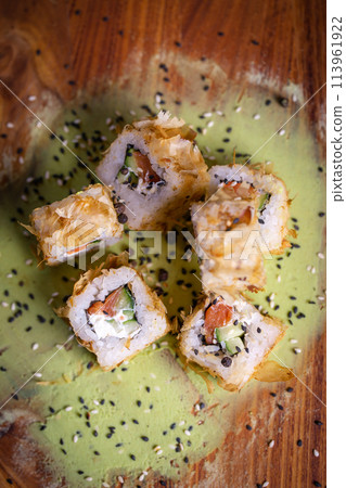 Deep-fried sushi roll with salmon and cucumber on the wooden plate Deep-fried sushi roll with salmon and cucumber on the wooden plate 113961922