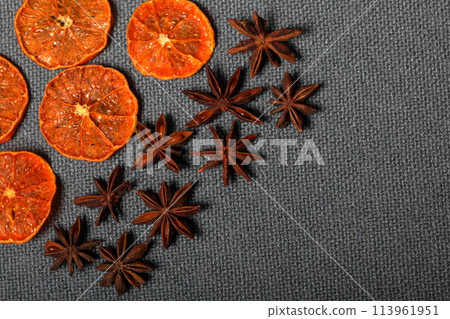 Tangerines are cut into slices and dried to decorate desserts. Nearby are the stars of anise. On a gray background. 113961951
