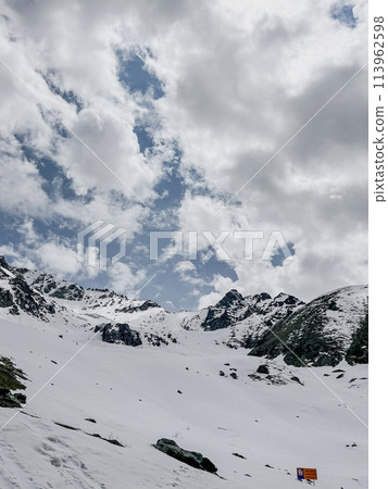 Snowy mountain landscape with blue sky and clouds for travel or tourism brochure 113962598