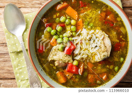 Aguadito de pollo Peruvian soup with cilantro, vegetables and chicken closeup on the bowl. Horizontal top view 113966010