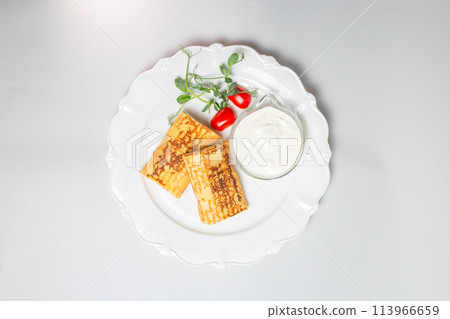 Top view of Pancakes with sour cream and cherry tomatoes on a white background. Carnival menu Top view of Pancakes with sour cream and cherry tomatoes on a white background. Carnival menu 113966659