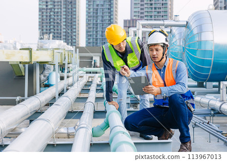 engineer teamwork technician workers service hotel boiler tank hot water supply pipe system. team working safety checking maintenance pipeline heating water delivery line at roof top outdoor. 113967013