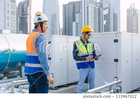 engineer male technician worker working service commercial building heat pump hot water supply systems. man safety checking maintenance heating water machine at roof top outdoor. 113967022