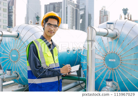 portrait asian male engineer worker work on site service maintenance hot water tank at roof top outdoor hotel building. 113967029