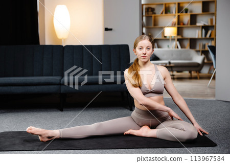 Young sporty woman practicing yoga, doing Revolved Head to Knee Forward exercise, wearing sportswear, sitting on the floor in living room Young sporty woman practicing yoga, doing Revolved Head to Knee Forward exercise, wearing sportswear, sitting on the floor in living room 113967584