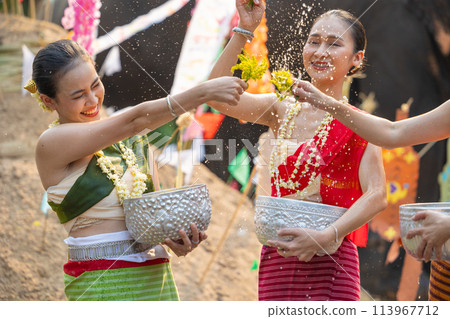 Songkran festival. Northern Thai people in Traditional clothes dressing splashing water together in Songkran day cultural festival with sand pagoda and colorful paper flag. Songkran festival. Northern Thai people in Traditional clothes dressing splashing water together in Songkran day cultural festival with sand pagoda and colorful paper flag. 113967712