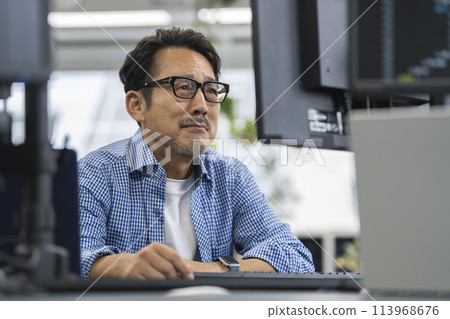 A man in his 50s staring at a computer monitor A man in his 50s staring at a computer monitor 113968676