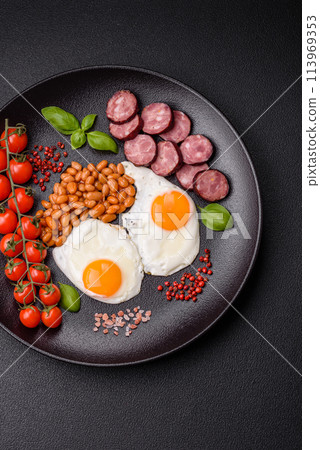 English breakfast with fried eggs, bacon, beans, tomatoes, spices and herbs 113969353