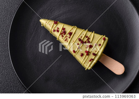 Delicious sweet cheesecake with fruits covered with icing with a wooden stick Delicious sweet cheesecake with fruits covered with icing with a wooden stick 113969363