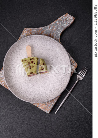 Delicious sweet cheesecake with fruits covered with icing with a wooden stick 113969398