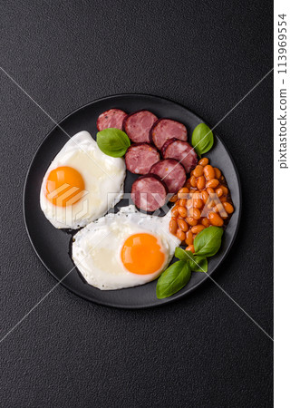 English breakfast with fried eggs, bacon, beans, tomatoes, spices and herbs English breakfast with fried eggs, bacon, beans, tomatoes, spices and herbs 113969554