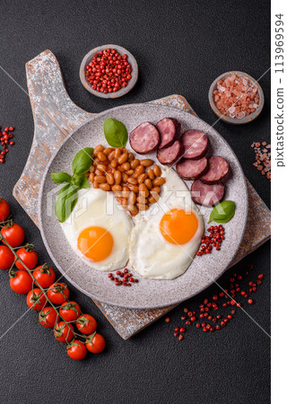 English breakfast with fried eggs, bacon, beans, tomatoes, spices and herbs English breakfast with fried eggs, bacon, beans, tomatoes, spices and herbs 113969594