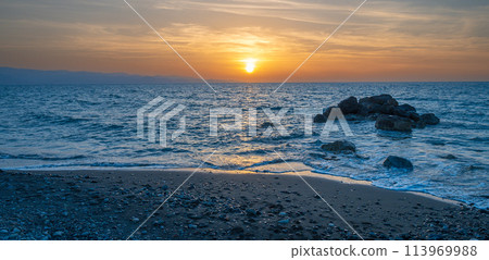 Sunset by the sea, the sky is reflected in the smooth sea 113969988