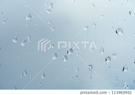Glass with rain drops against gray background. 113969992