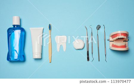 Mouthwash, toothpaste tube, dental floss and medical mirror on a blue background, oral hygiene. Mouthwash, toothpaste tube, dental floss and medical mirror on a blue background, oral hygiene. 113970477
