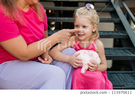 Child girl with cochlear implant with her mother spend time outdoor. Hear impairment and deaf community concept. Deaf and health concept. Disability and inclusion. Copy space 113970611