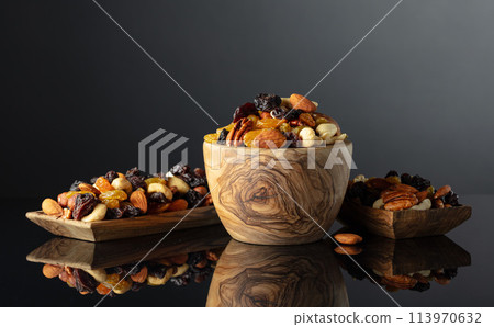 Mix of various nuts and raisins on a black reflective background. 113970632