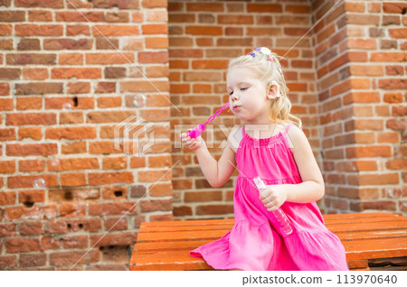 Child girl walks and have fun outdoor with cochlear implant on the head. Hearing aid and treatment concept. Inclusion and disability. 113970640