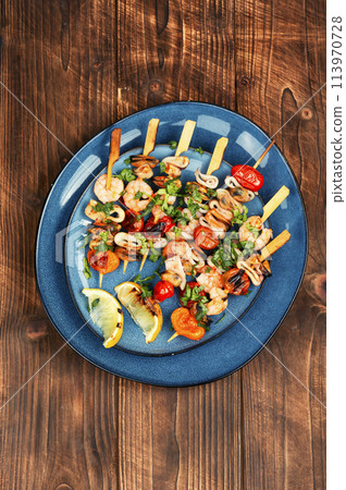 Seafood kebabs on wooden background. Seafood kebabs on wooden background. 113970728