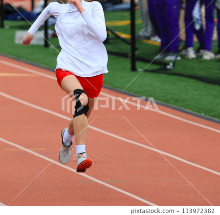 Ond girl running a sprint race on a track wearing KT tape on her knee Ond girl running a sprint race on a track wearing KT tape on her knee 113972382