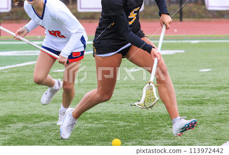 Girls lacrosse players chasing the ball during a game Girls lacrosse players chasing the ball during a game 113972442