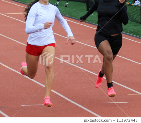 Two girls running a race on a track outdoor in lanes 113972443