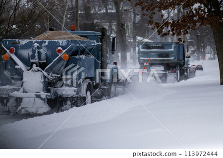 Two snowplows clearing a road and dropping sand 113972444